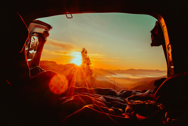 Photo d’un lever de soleil vu depuis le coffre d’une voiture, capturant l’essence du voyage et l’évasion des road-trips.